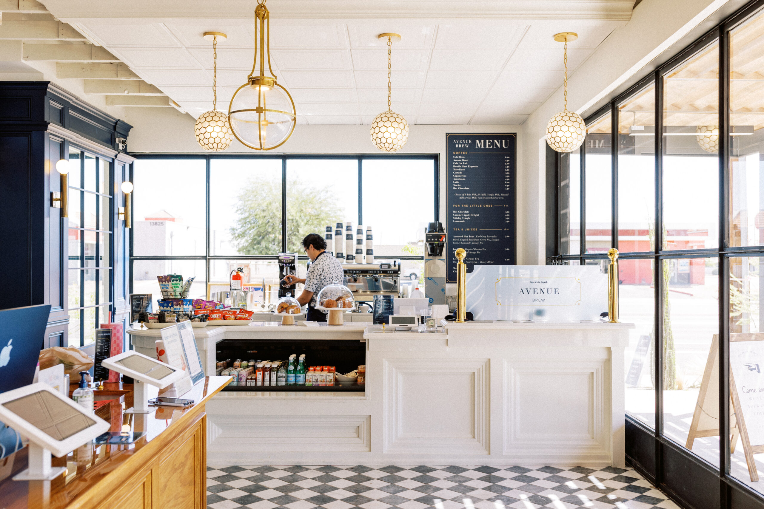 Avenue Brew interior with gold pendant lights, white counter, and checkered floor