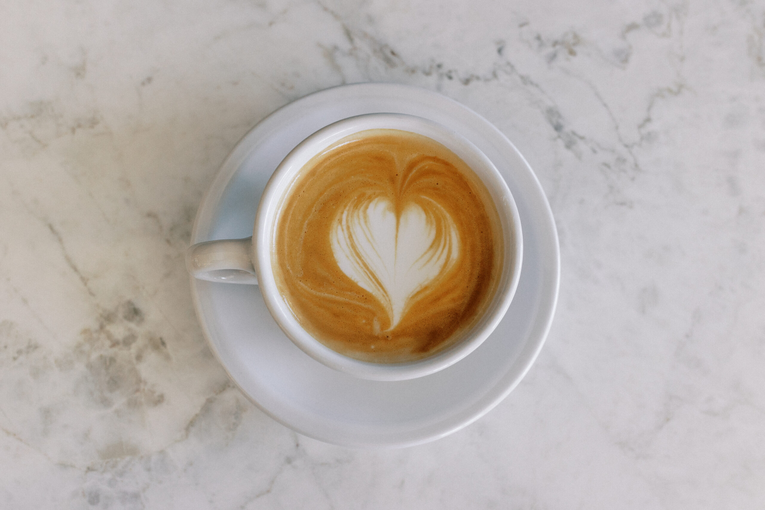 Overhead view of latte heart art on marble countertop at Avenue Brew